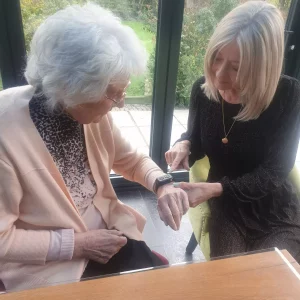 A woman showing her elderly mother how to use a fall detection watch